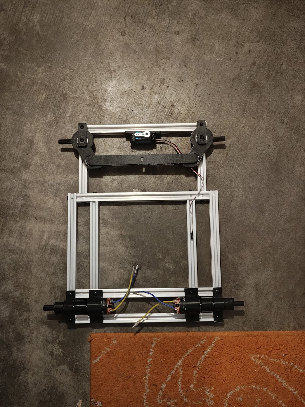Aluminum frame with white 3D-printed motor mounts and steering components attached