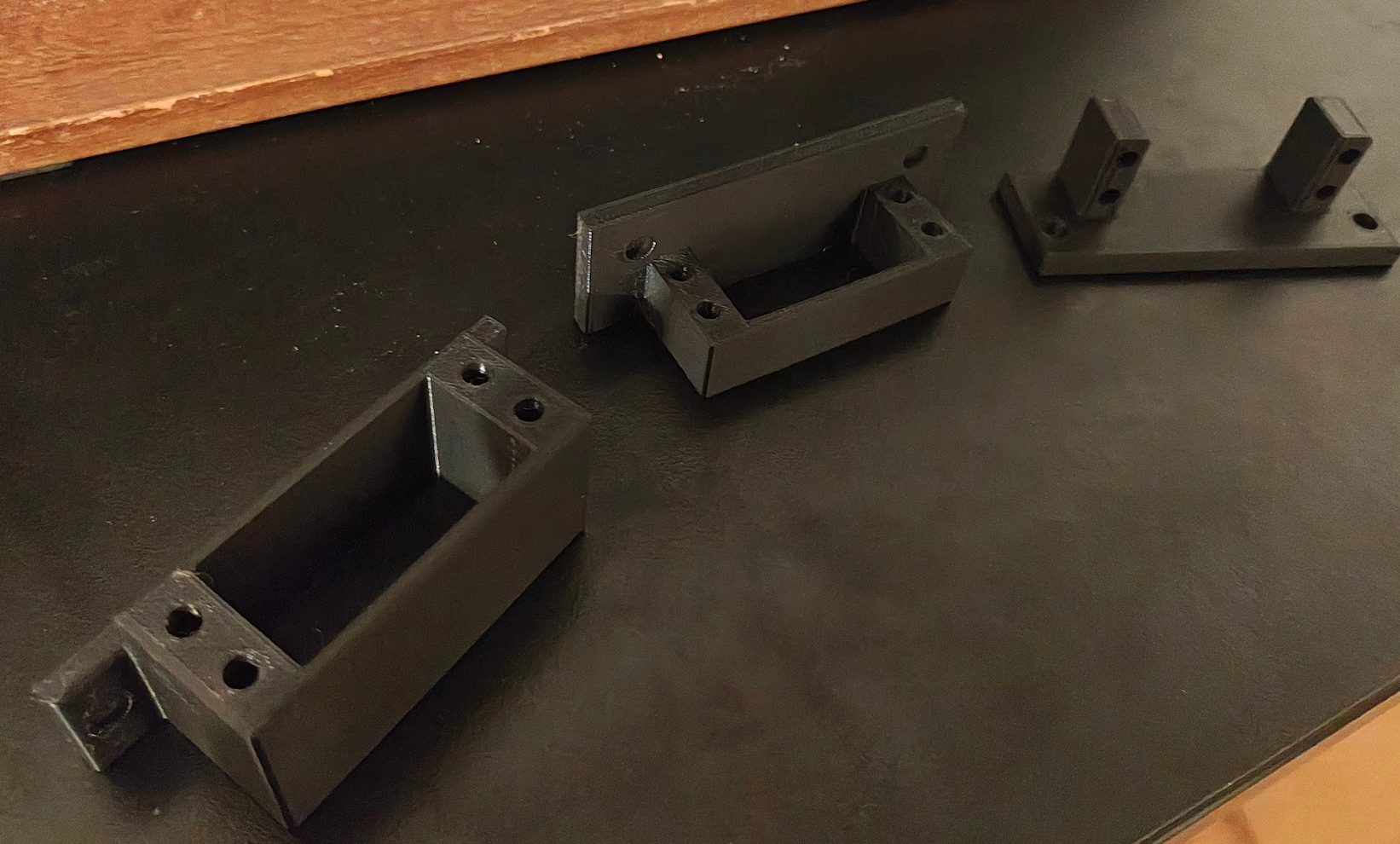 Four white 3D-printed servo mounts arranged in a row showing design progression