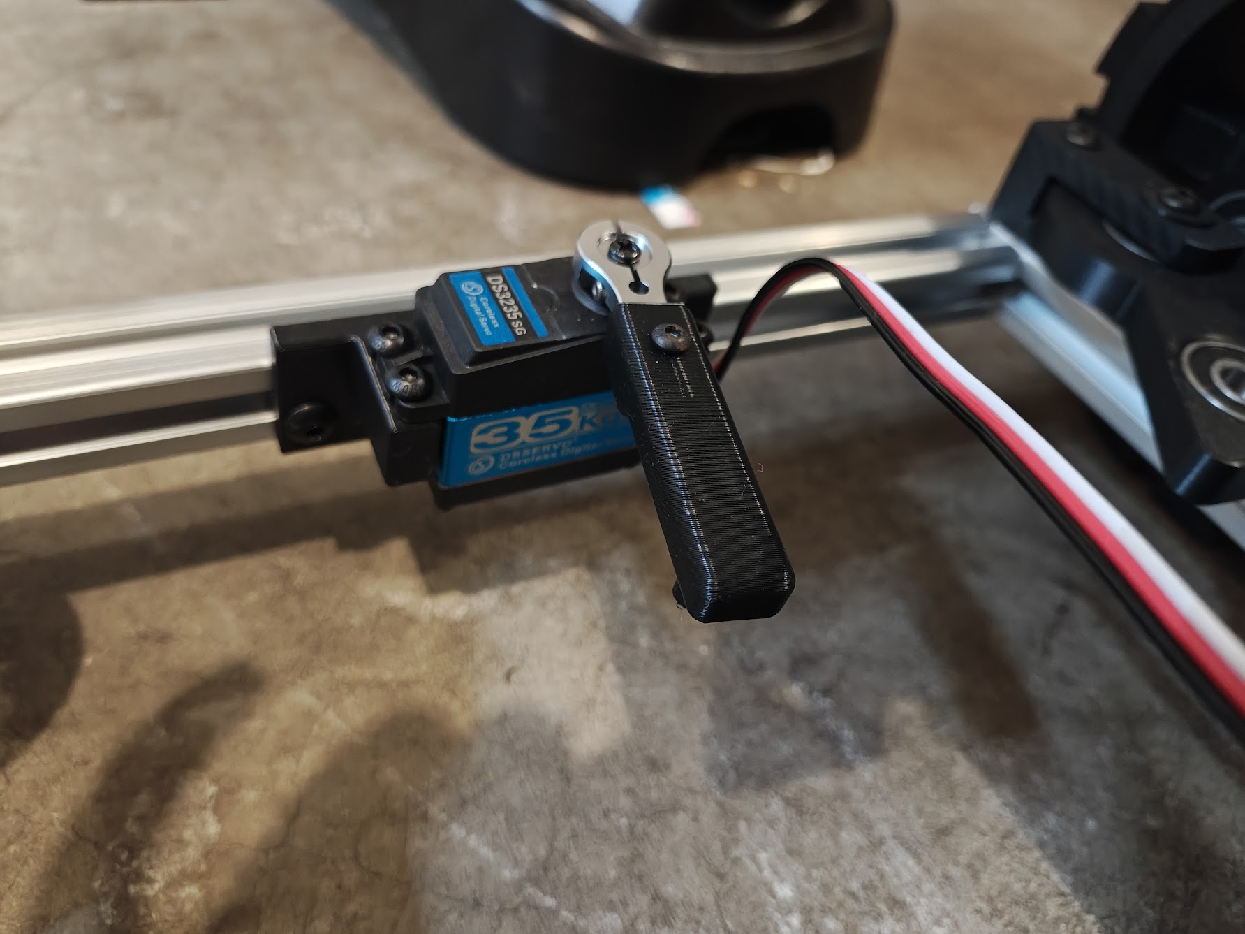 Blue servo motor installed in white mount with custom steering arm attached