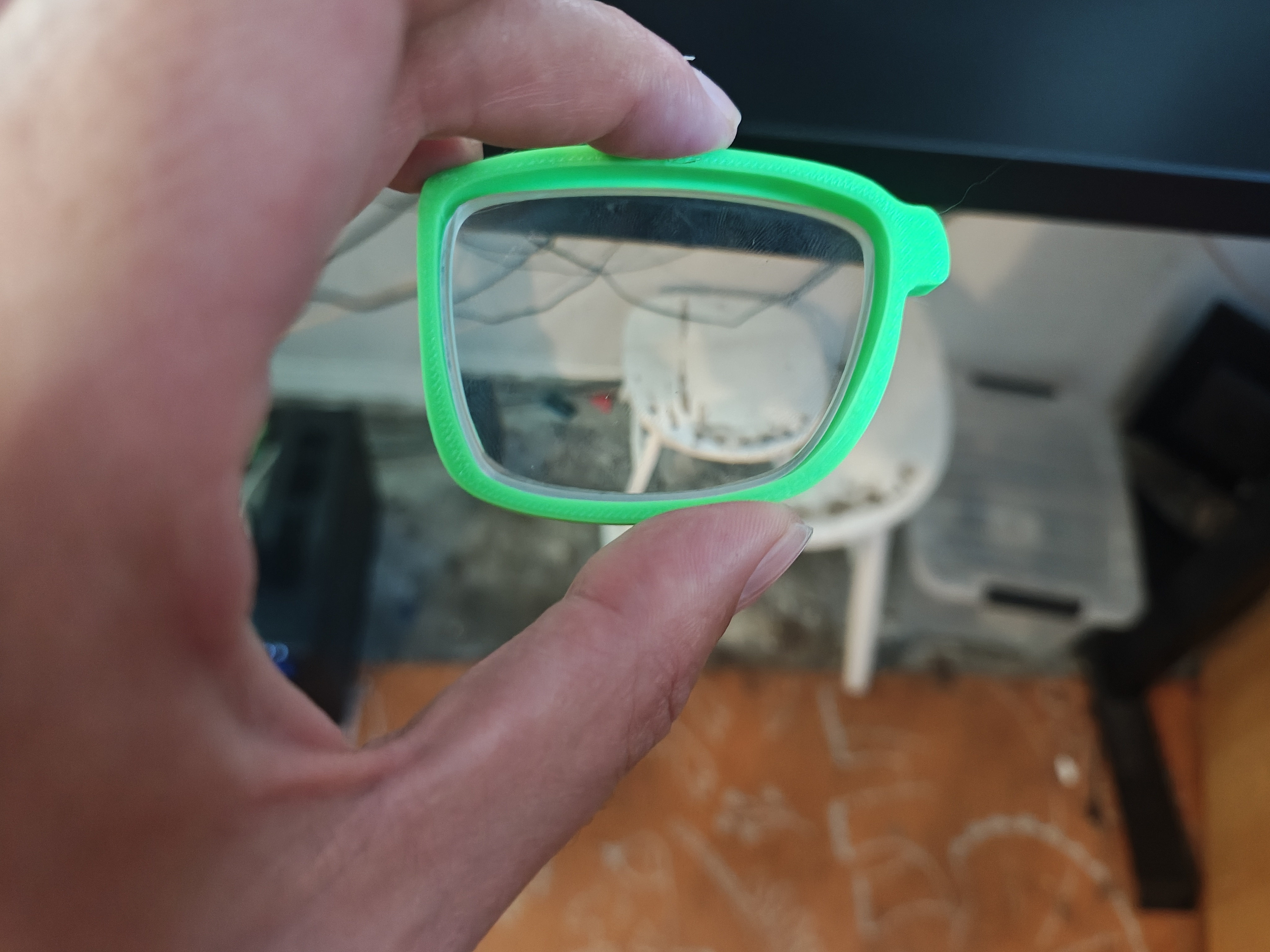 Green prototype frame held up with prescription lens installed
