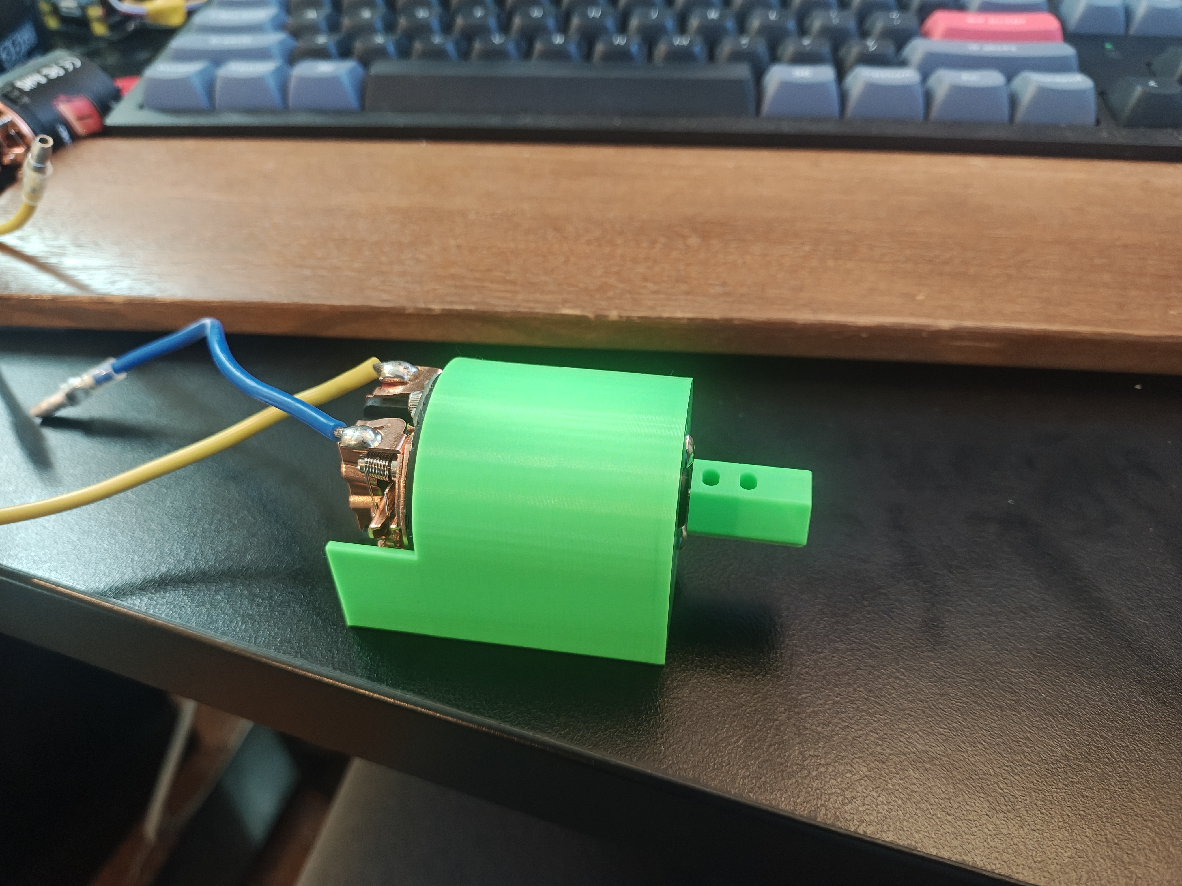 White 3D-printed motor mount with silver flexible coupler connecting motor shaft to axle