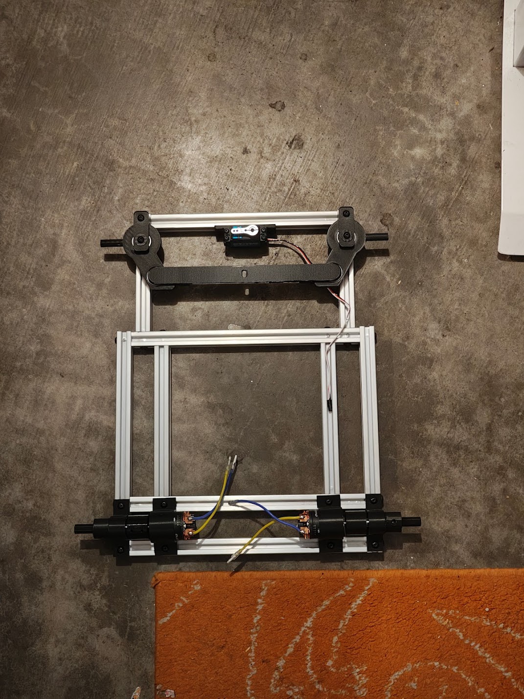 Top-down view of aluminum frame with steering knuckles and servo mounted, before steering arm installation