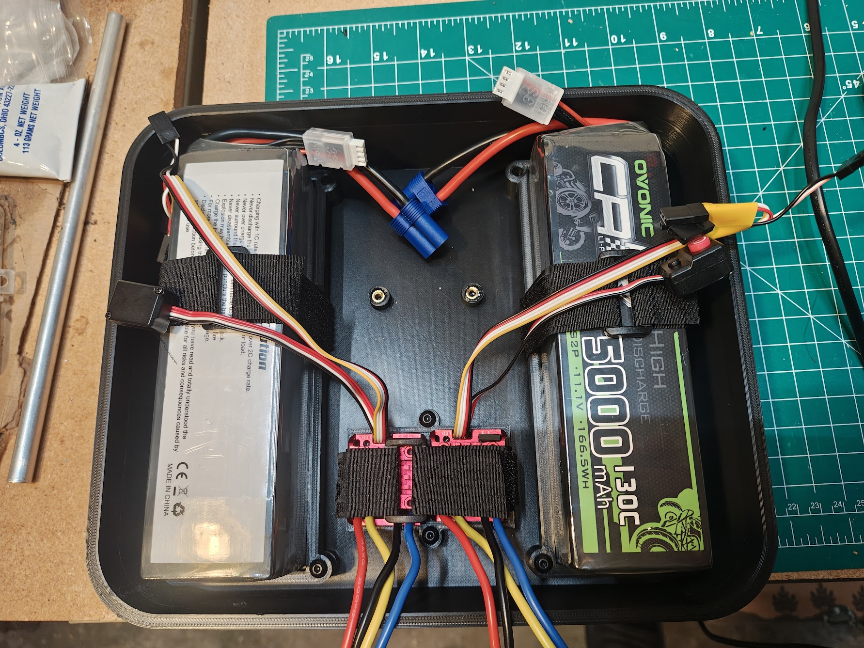 Inside of enclosure showing white 3D-printed trays holding batteries and electronics with velcro straps