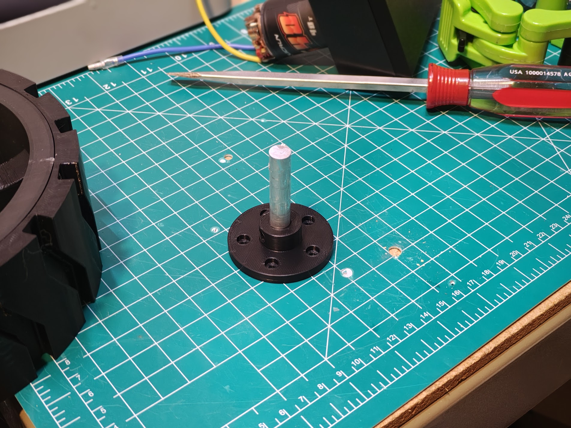 Black 3D-printed wheel hub with 5-lug bolt pattern and metal shaft