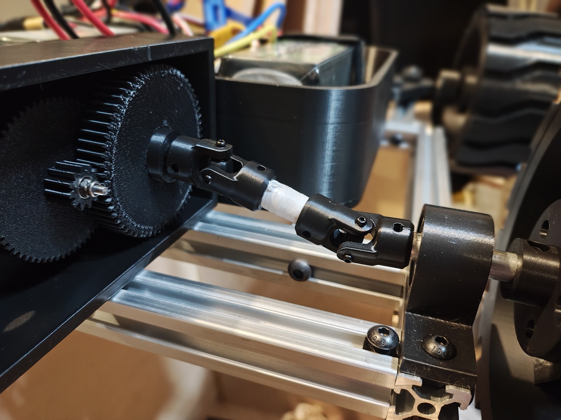 Dual cardan universal joint connecting gearbox output shaft to wheel hub on aluminum frame