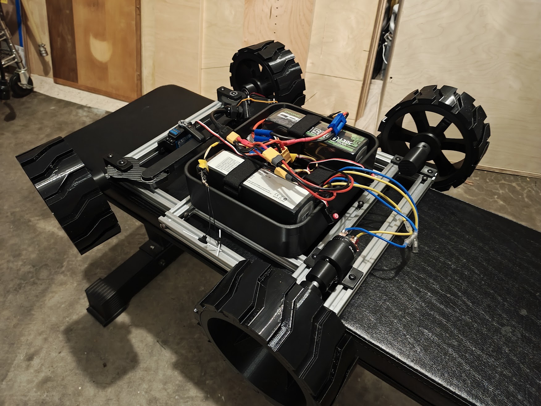 Assembled rover with all four wheels, steering, and electronics enclosure on garage floor